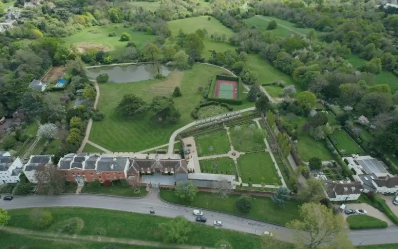 Aerial view of a red-brick house with walled gardens and a lake in Barnet