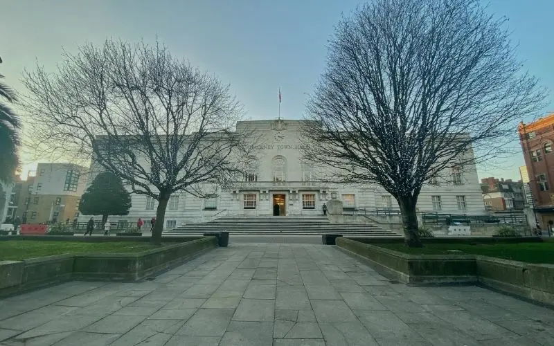 The stone front of Hackney Town Hall between two bare trees