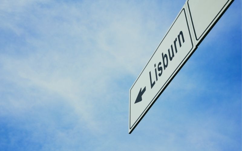 Road sign pointing towards Lisburn against a blue sky