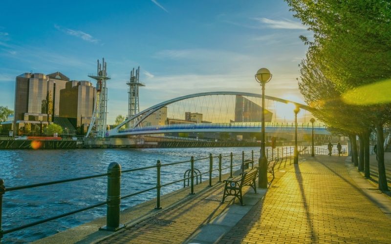 Salford Quays waterfront promenade with the Millennium footbridge at sunset