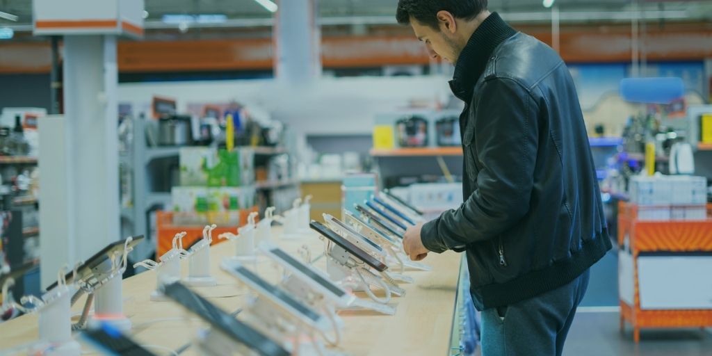 Person comparing phones on display in an electronics shop